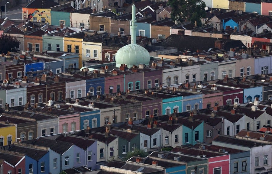 Rows of multicolored houses photographed from above, with a mint-green dome and minaret at their center