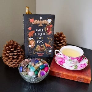 Call Forth a Fox with a pinecone, teacup, and a small fox figurine
