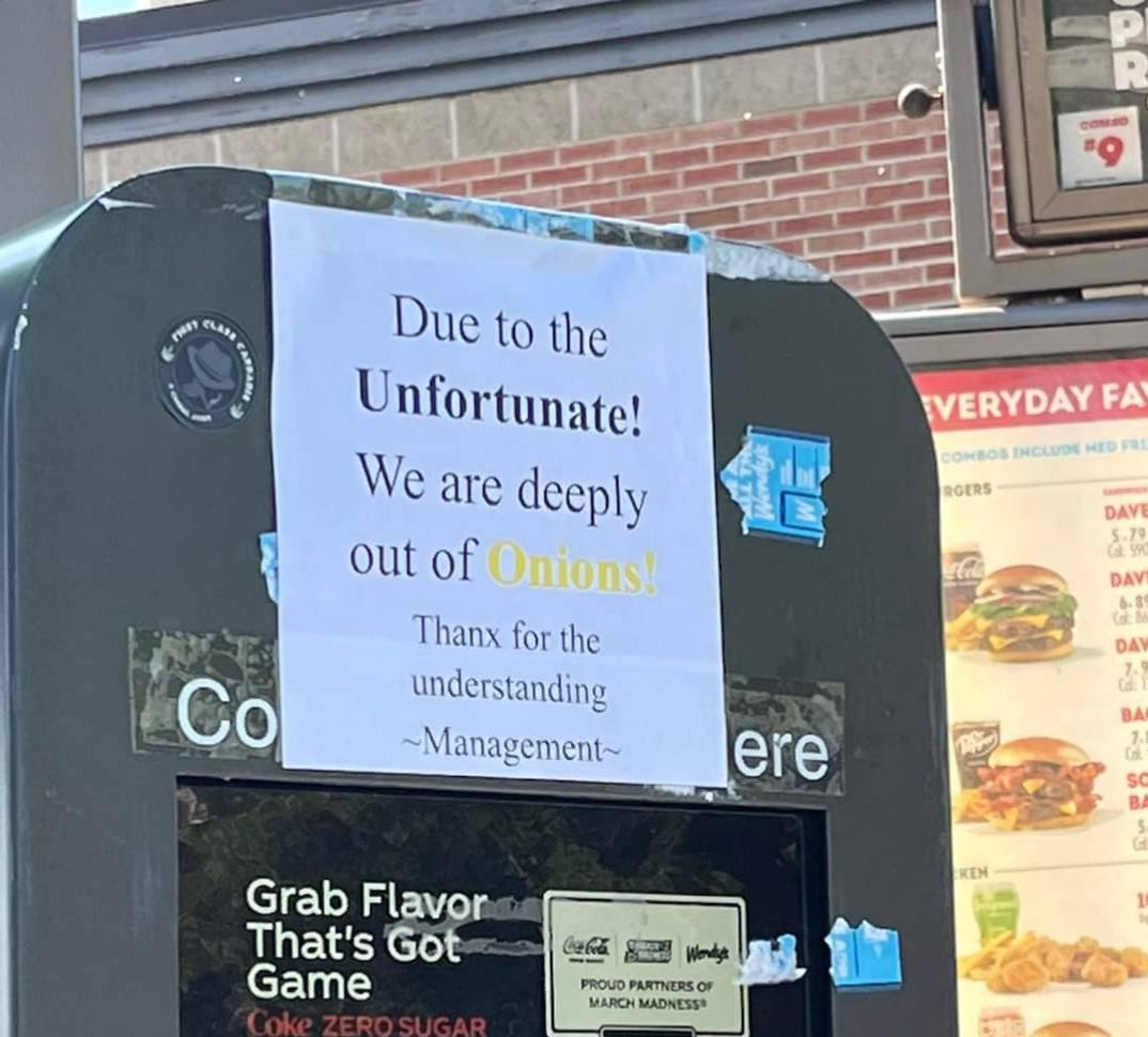 Photo of a printed paper sign at a drive through which reads: “Due to the Unfortunate! We are deeply out of Onions! Thanx for the understanding ~Management~”