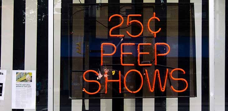 Photo of a neon sign advertising naughty peep-shows.