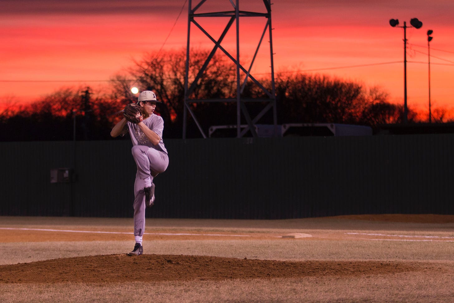 Baseball pitcher pitching at sunset