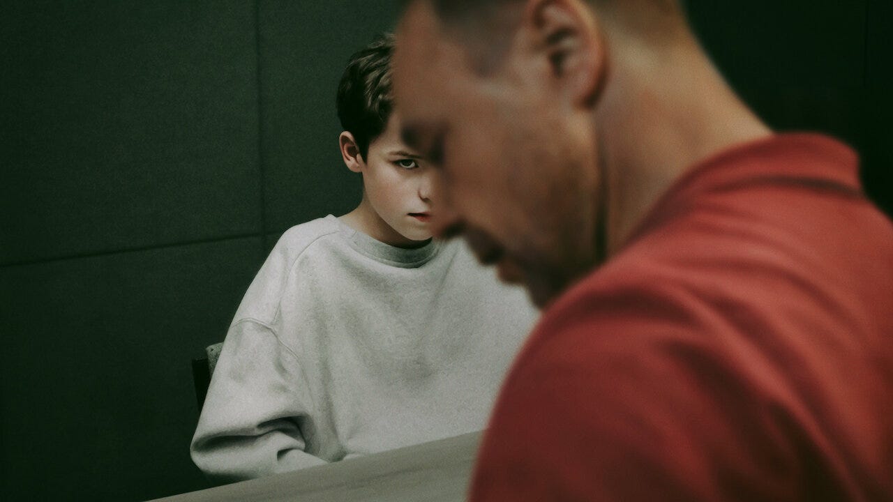 Jamie Miller sits beside his father, Eddie Miller, in a tense scene from Netflix’s Adolescence, both facing the camera with stiff body language. Adolescence Netflix