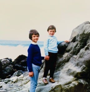 A couple of boys standing on a rock

Description automatically generated