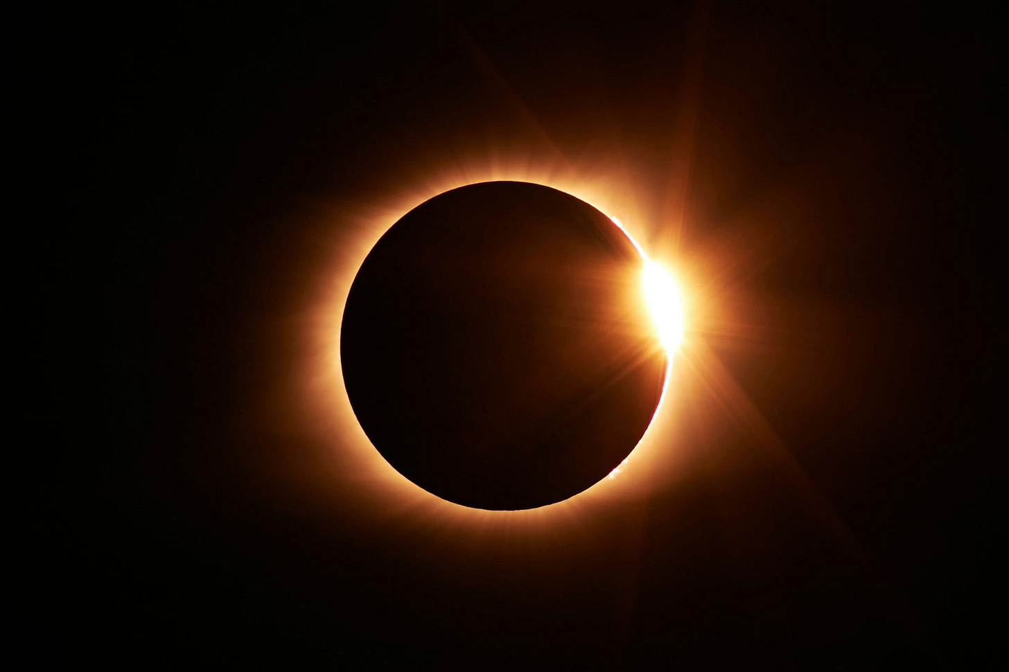 Solar eclipse with bright point of sunlight just emerging from the moon's edge at right of image Solar eclipse with bright point of sunlight just emerging from the moon's edge at right of image