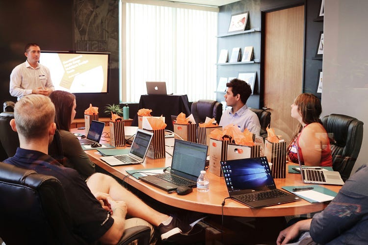 People sitting around a table listening to a speaker giving a presentation.