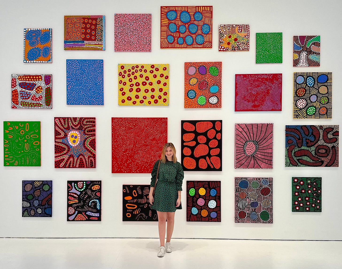 Casey Betts, Senior Social Media Manager at the Whitney Museum of American Art, standing in front of a wall of art