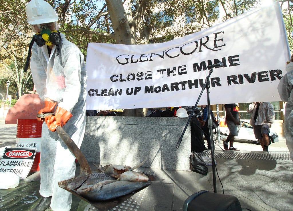 Lock the Gate alliance protest in Sydney Australia with a masked protestor dressed as a worker holding a shovel in front of a sign that reads Glencore Close the Mine Clean the McArthur River. NT Borroloola Indigenous travel to Glencore in Sydney "Stop polluting our land and waterways and make Glencore pay for closure and clean up at the McArthur River Mine" - that's the message from Traditional Owners from the Borroloola Indigenous clan groups in the Northern Territory who have traveled to Glencore in Sydney this morning.  The peaceful action coincides with the company's AGM in Switzerland and an international day of action where local communities impacted by Glencore’s mines will highlight the impacts on the essentials of life and community.  The Borroloola clan has been impacted by significant environmental problems caused by Glencore's reckless mining at McArthur River lead and zinc mine. The action was hosted by Action Aid, Mineral Policy Institute and the Borroloola clan groups of which a delegation of eight Elders and young people attended the action in Sydney.  Share and like to support the Borroloola Indigenous clan groups in the NT.  #‎Glencore #‎makethempay #‎minerehab
