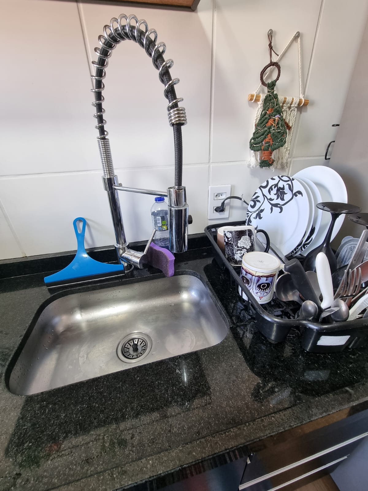 Foto da pia do apartamento em que moro, mostrando o escorredor cheio de pratos, canecas e talheres devidamente lavados.