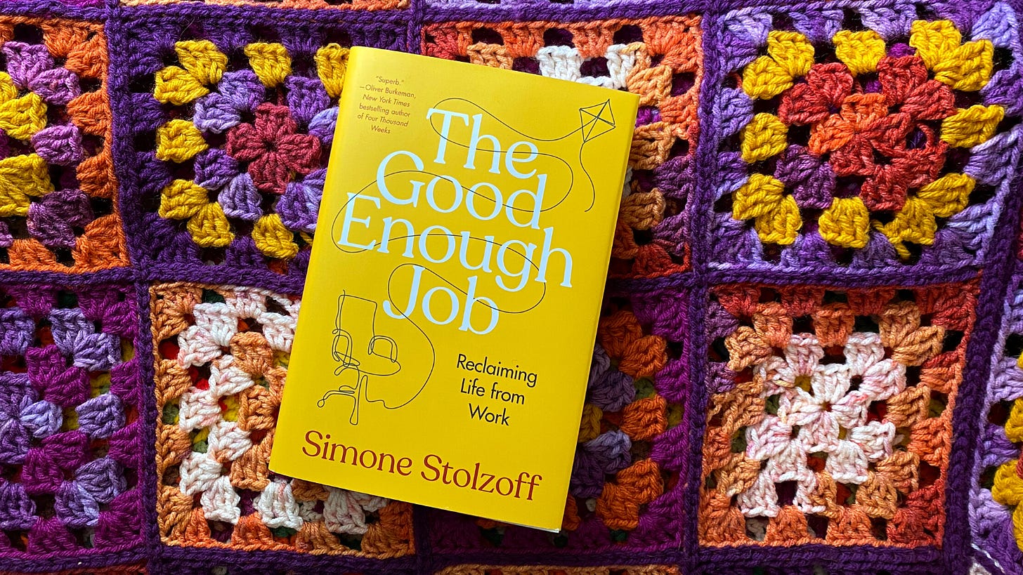 A copy of the book "The Good Enough Job" by Simon Stolzoff. The book is yellow and lying on a purple, orange, and yellow granny square crochet background