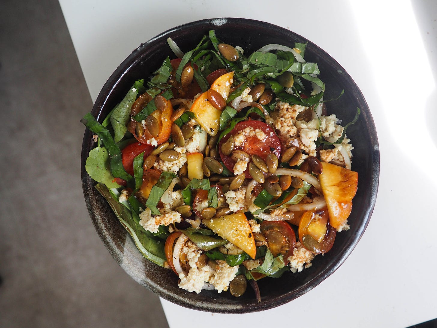 Tomato, peach and basil summer salad with onions, cheesy tofu and roasted pumpkin seeds.