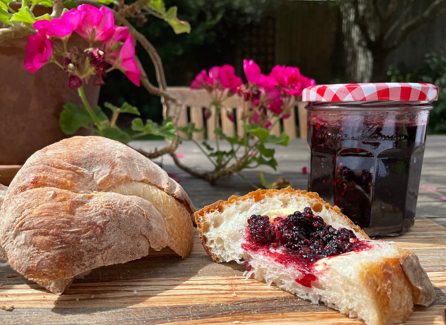 a pot of jam with a slice of buttered white bread with geranium 