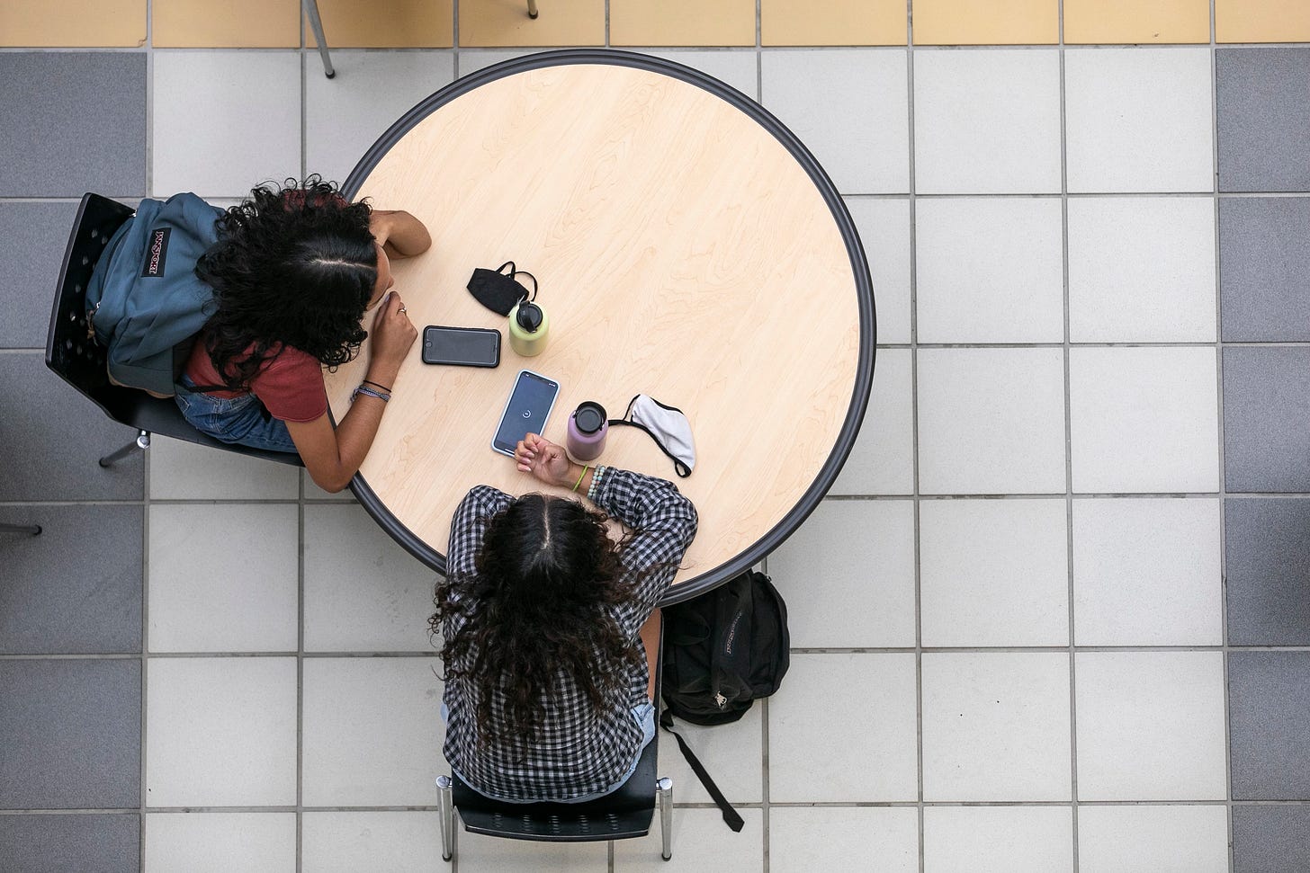 decorative image view from above two women sitting at a round table