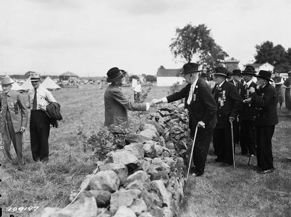 Union and Confederate veterans shaking hands over the rock wall at The Angle