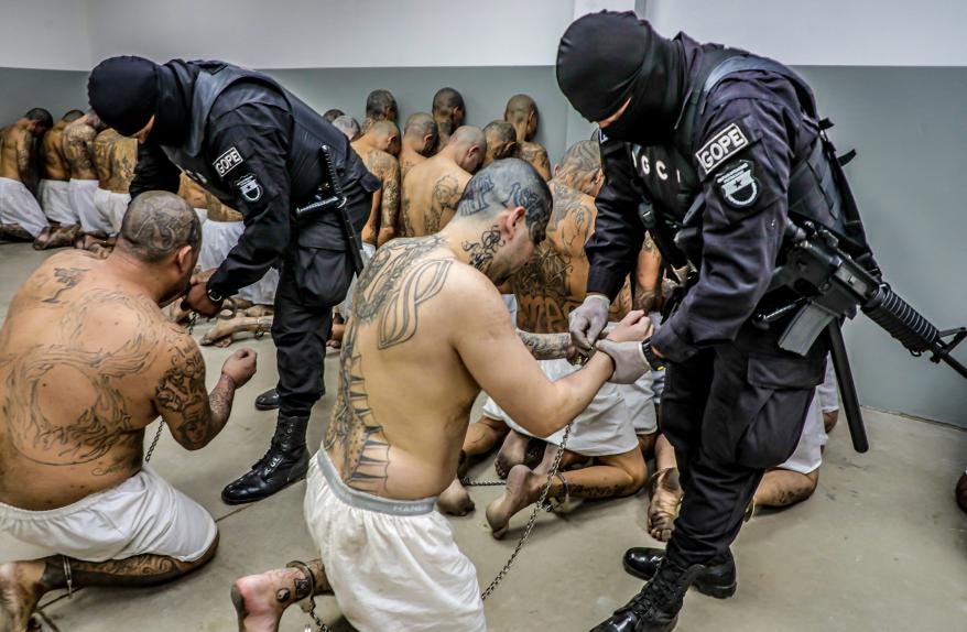 Prison agents guard gang members as they are processed.