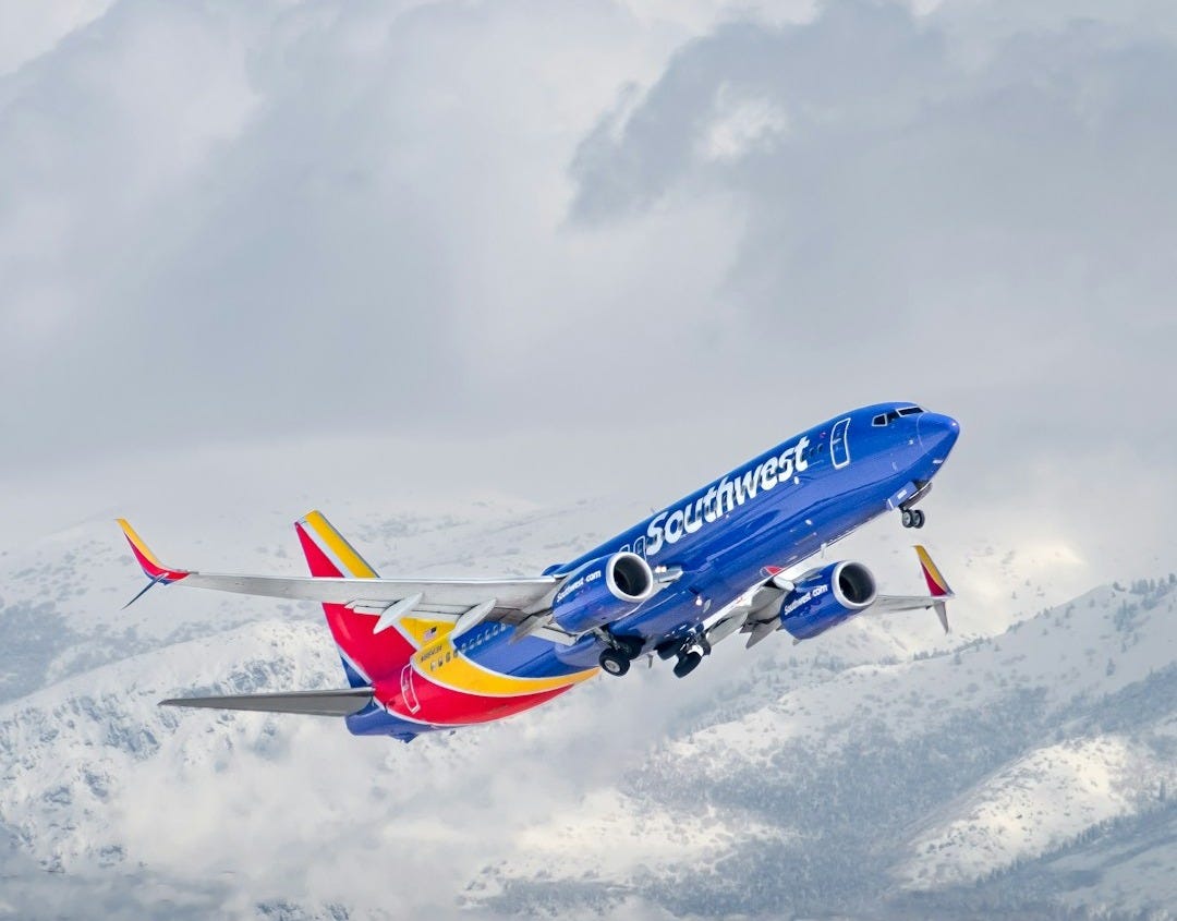 a blue and yellow plane flying over a mountain a blue and yellow plane flying over a mountain
