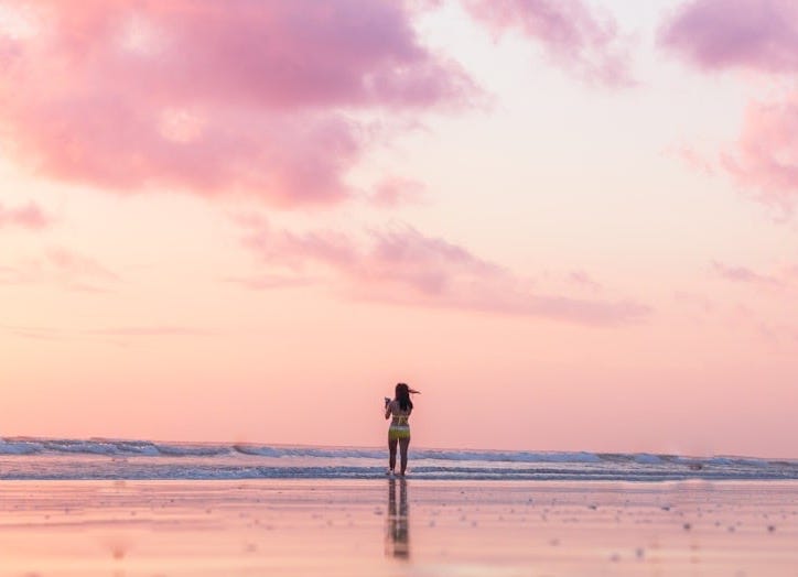 woman standing on seashore in front of body of water