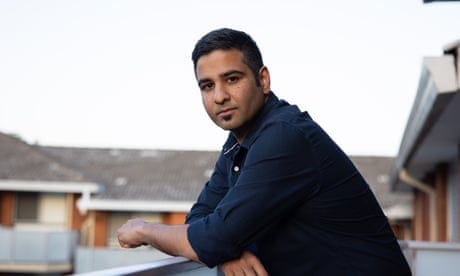 Nishadh Rego pictured leaning on his balcony at home wearing a blue shirt