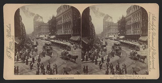 a photo of downtown chicago in 1893. Commercial district busy with pedestrians, trolleys, and horse drawn carts. 