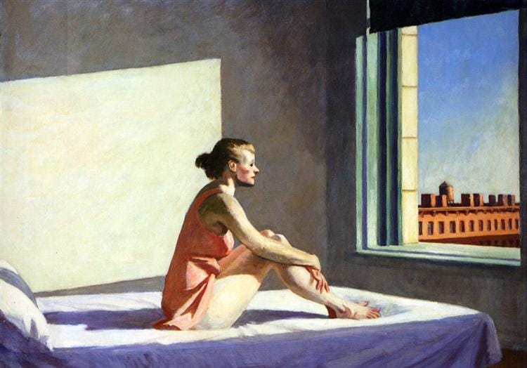 A woman on a bed gazes out toward the urban landscape, lost in thought, as the warm sunlight illuminates her form, casting sharp shadows within the room.