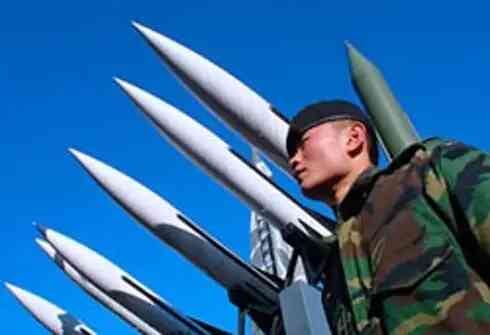 A North Korean soldier in the foreground, with missiles behind him.