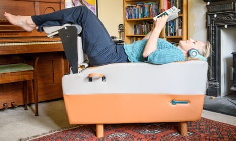 Linda Geddes lying on her back on the Backhug robotic masseuse in a room of her home