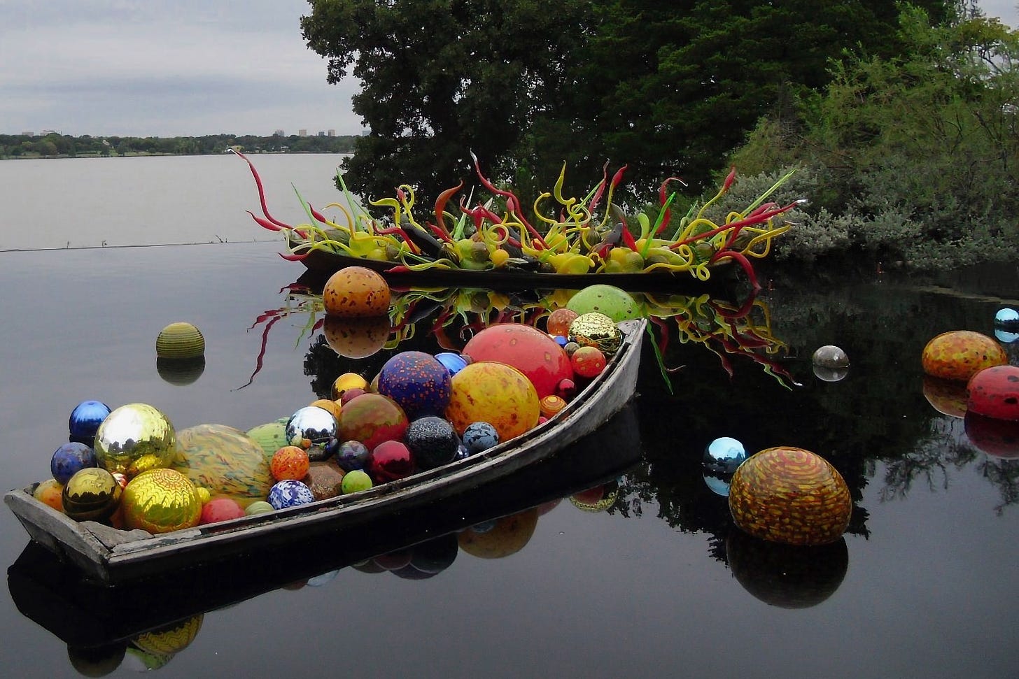 An installation of colorful orbs of Chihuly glass in a boat and also floating in the water