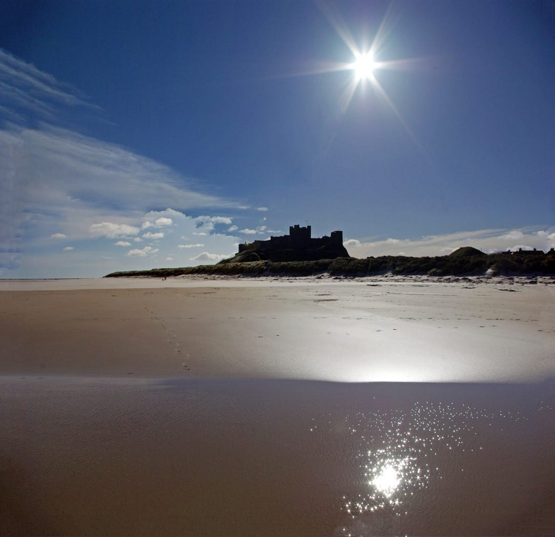 A sandy beach with a castle in the background