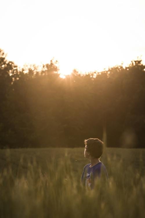 Free Boy Standing on Grass Field While Looking at the Horizon Stock Photo