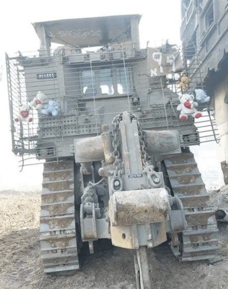 Picture of an Israeli bulldozer with a protective grate, decorated with stuffed animals.