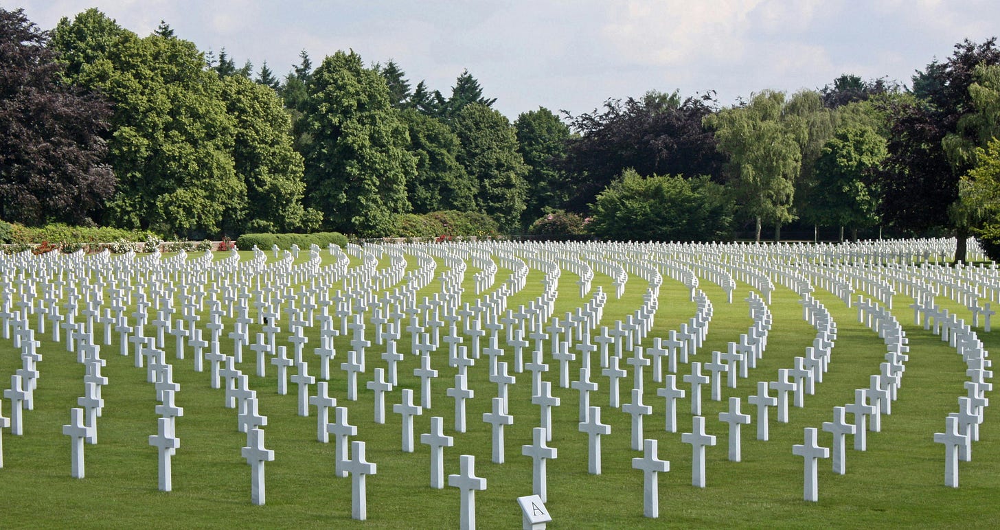 Free A serene military cemetery with rows of white crosses surrounded by lush greenery. Stock Photo