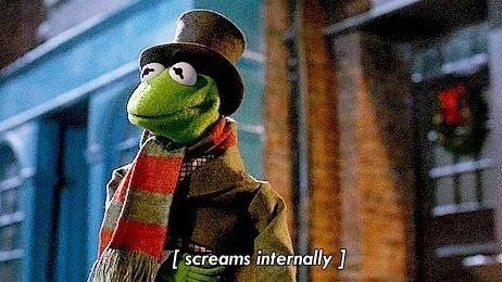 Kermit The Frog, wearing a Victorian outfit, stares into space. The subtitles say "[screams internally]".