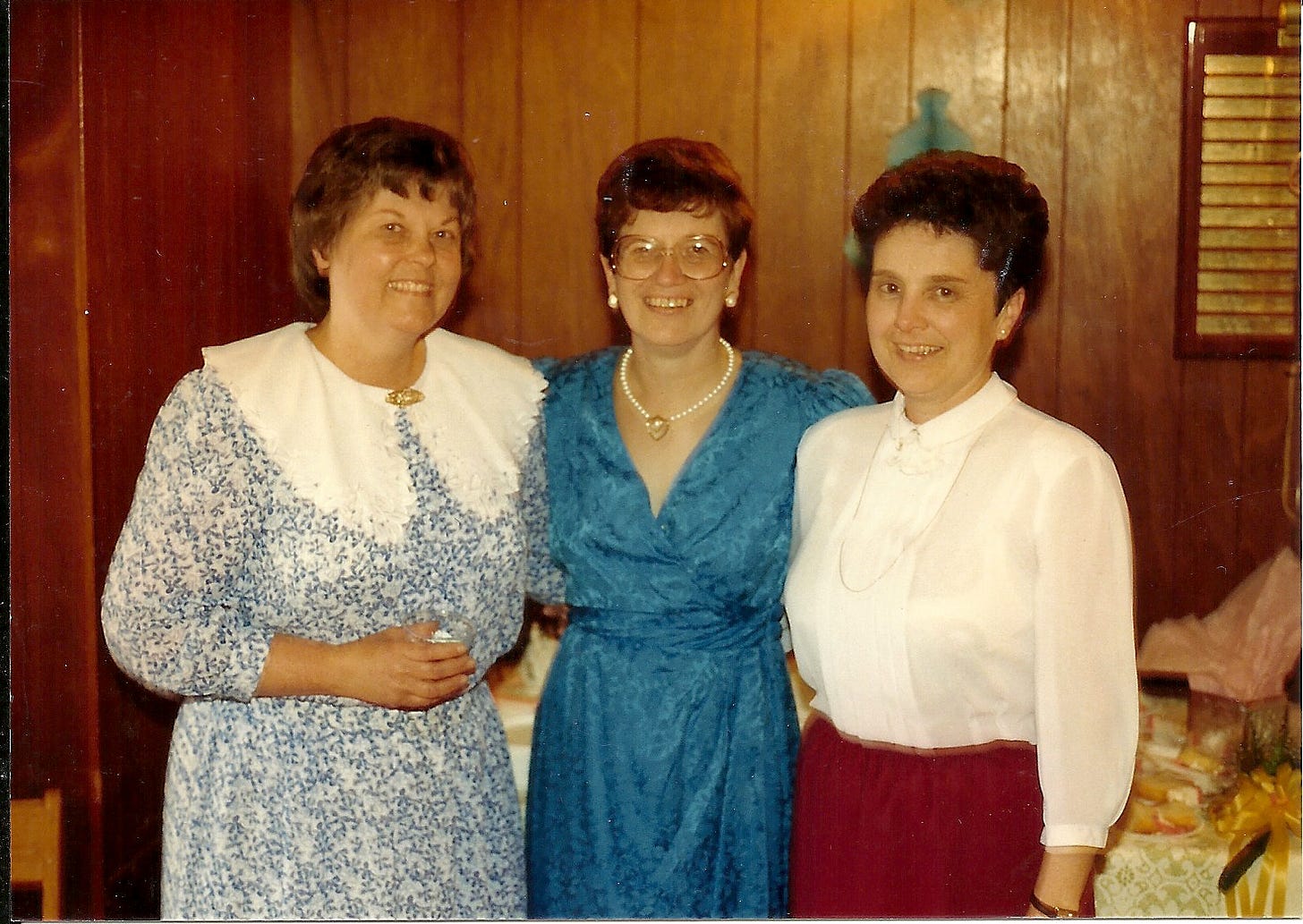 Three middle-aged women look gleeful to be posing for a photo