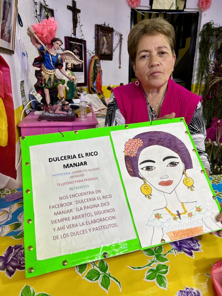 elderly mexican woman in hot pink holding sign for her bakery