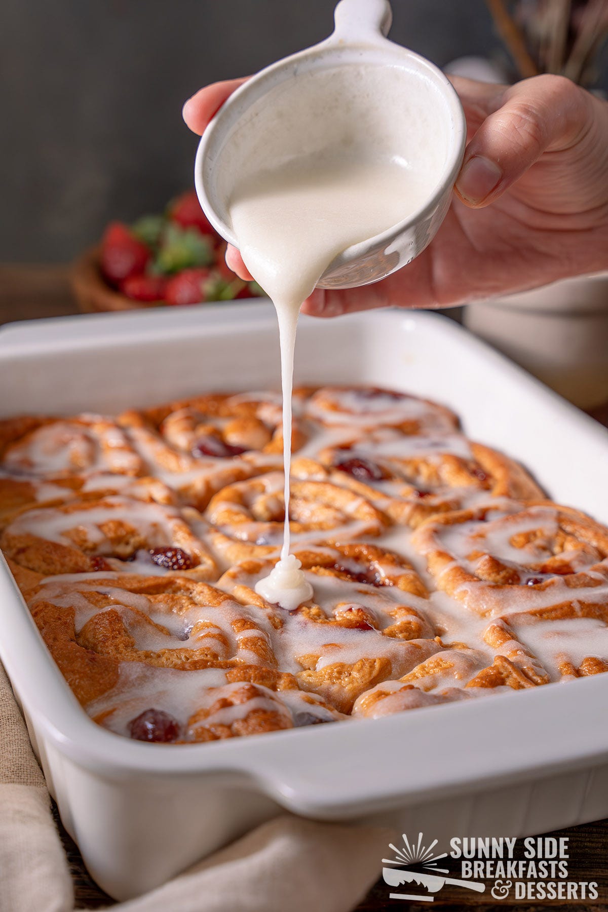 Pouring maple icing onto golden maple buns.