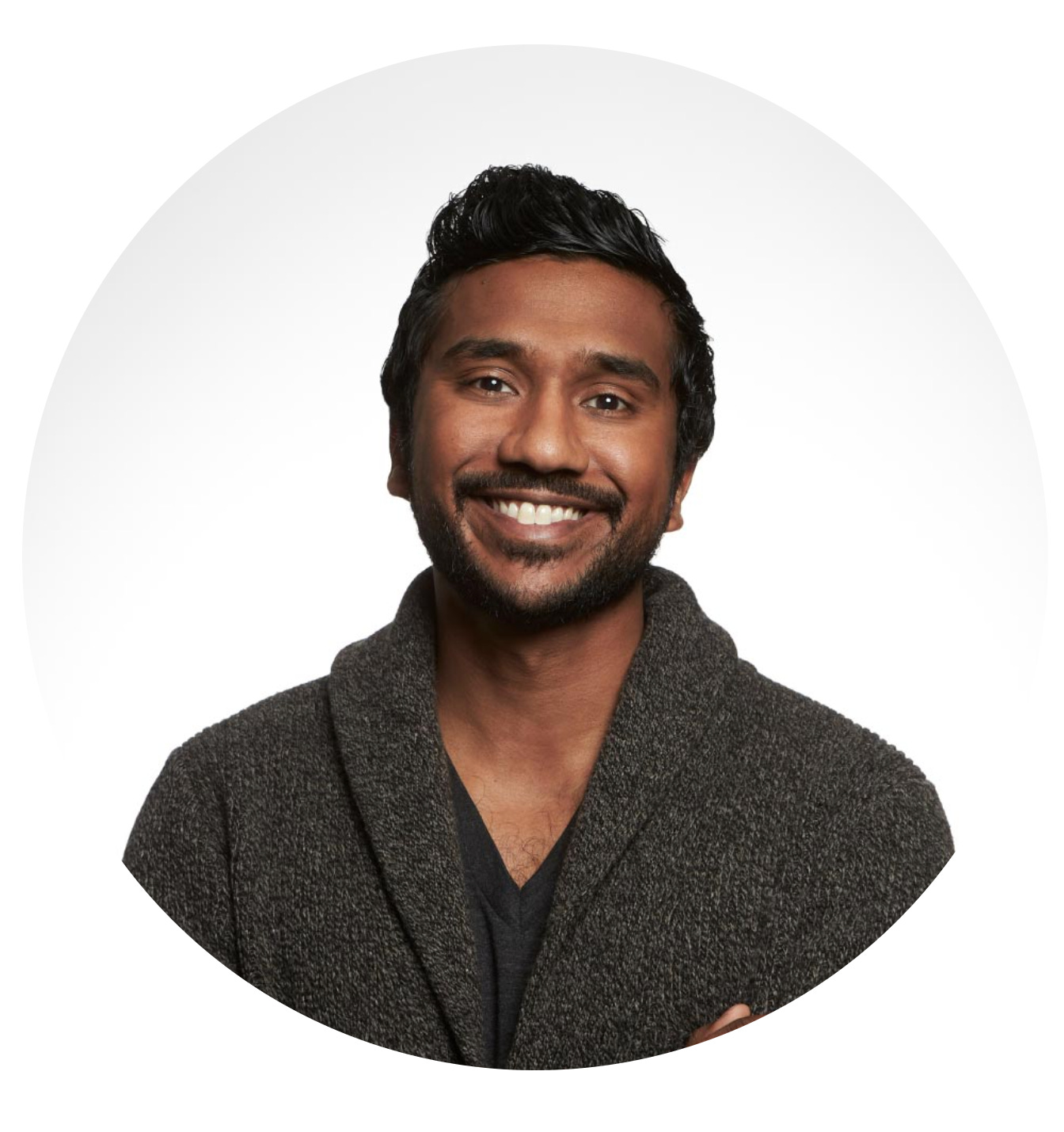 A photo of Ryan Panchadsaram, smiling broadly and wearing a charmingly cozy looking sweater.