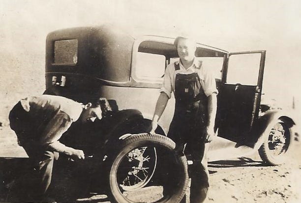 Photo from 1930s of two men fixing a flat on a Model T.