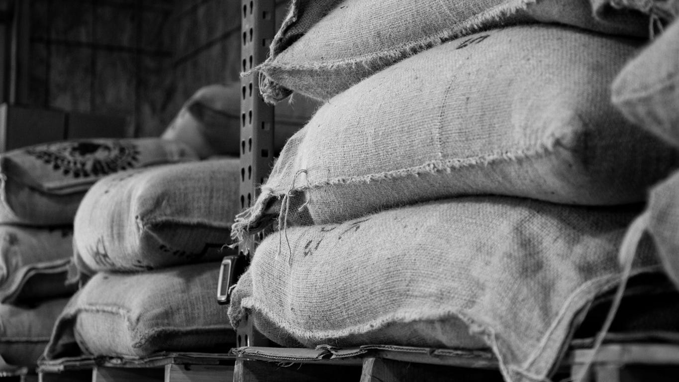 Piles of green coffee sacks in a row in a warehouse