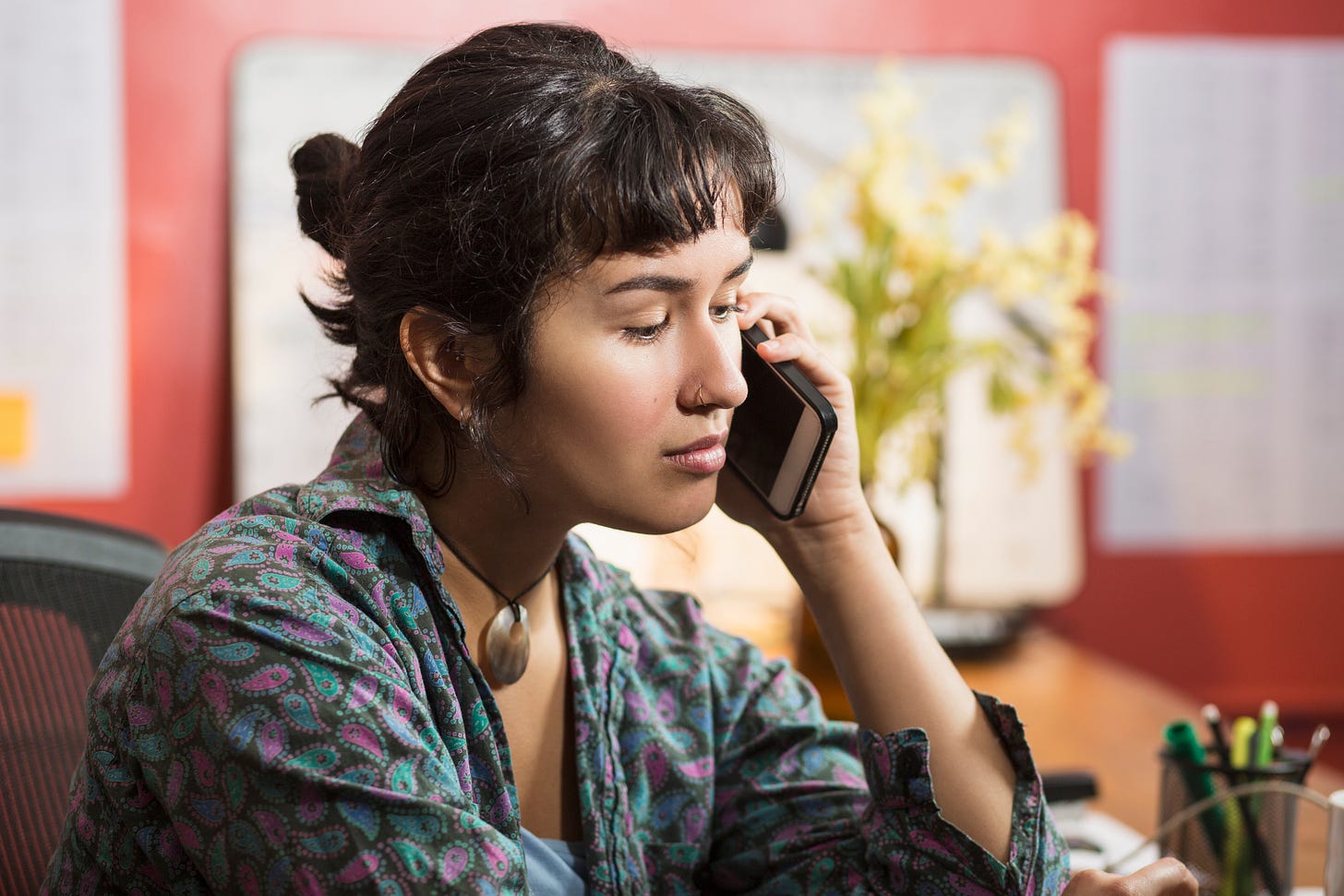 Latino woman on phone, wearing a blue and purple blouse calling a crisis pregnancy center