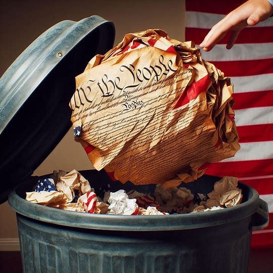the u.s. Constitution wadded into a ball and being tossed into a garbage can. Image 1 of 3