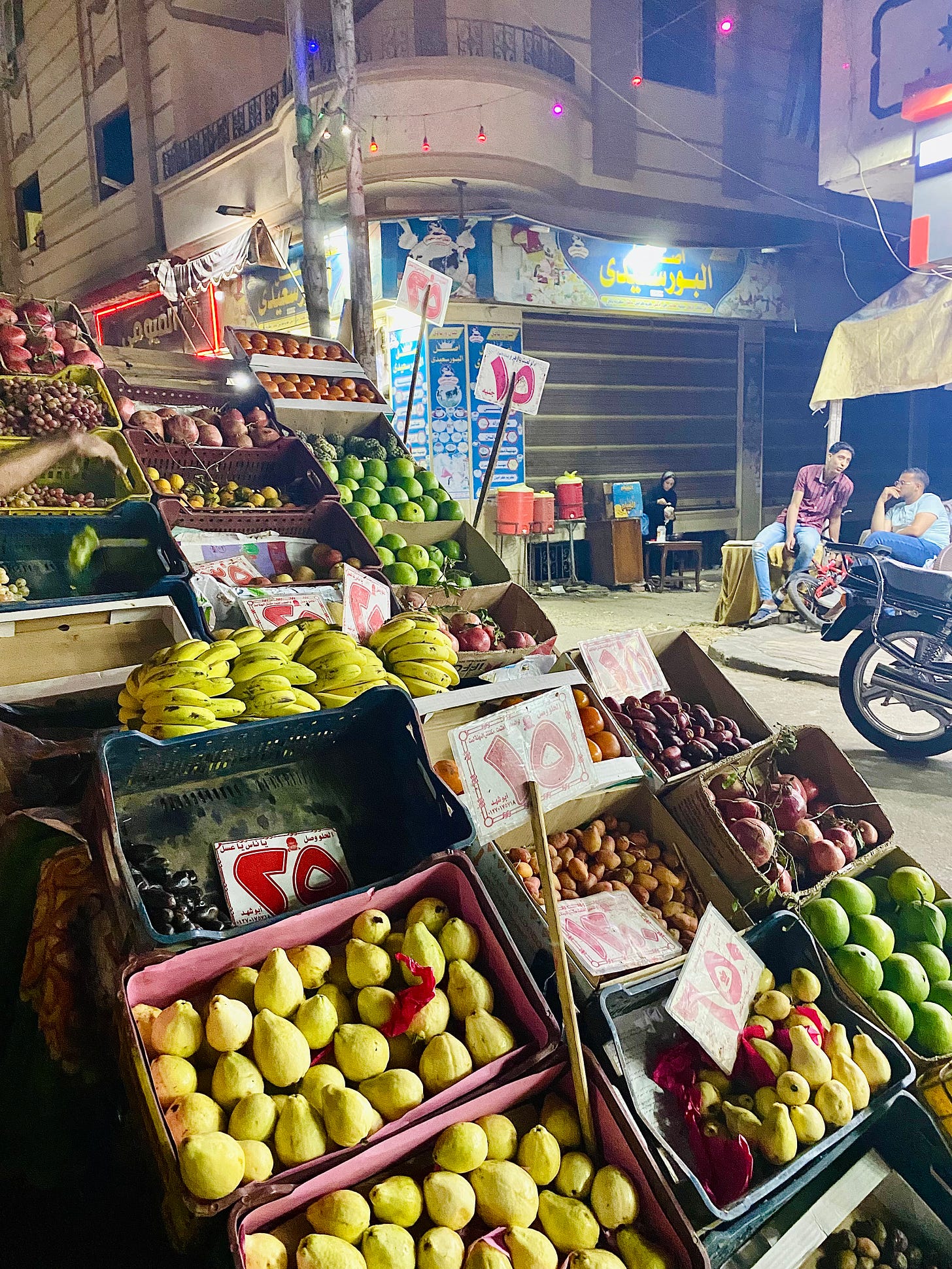 A fruit cart with guava, bananas, and dates on a city street