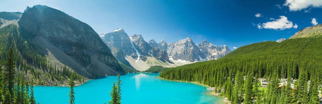 A panoramic view of mountains, forest, and a very blue lake.