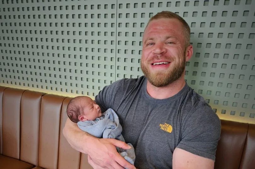 Cairan Gemmell, who died aged 32, holding a newborn baby on a brown sofa in front of some tan-coloured tables at a pub