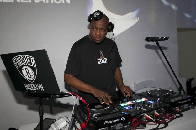 DJ at equipment focusing on mixing music with logo on laptop and wearing a branded t-shirt