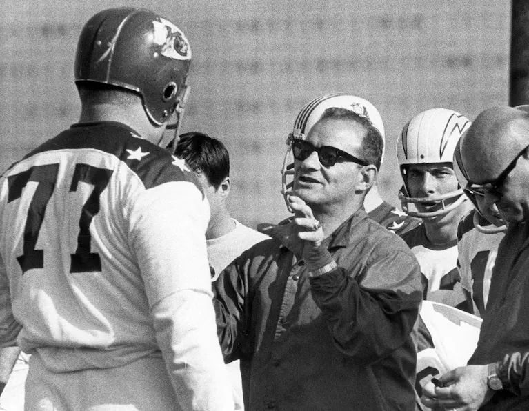Kansas City Chiefs offensive tackle Jim Tyrer (77) listening to coach Sid Gilman during a 1965 workout for the AFL All-Star Game.