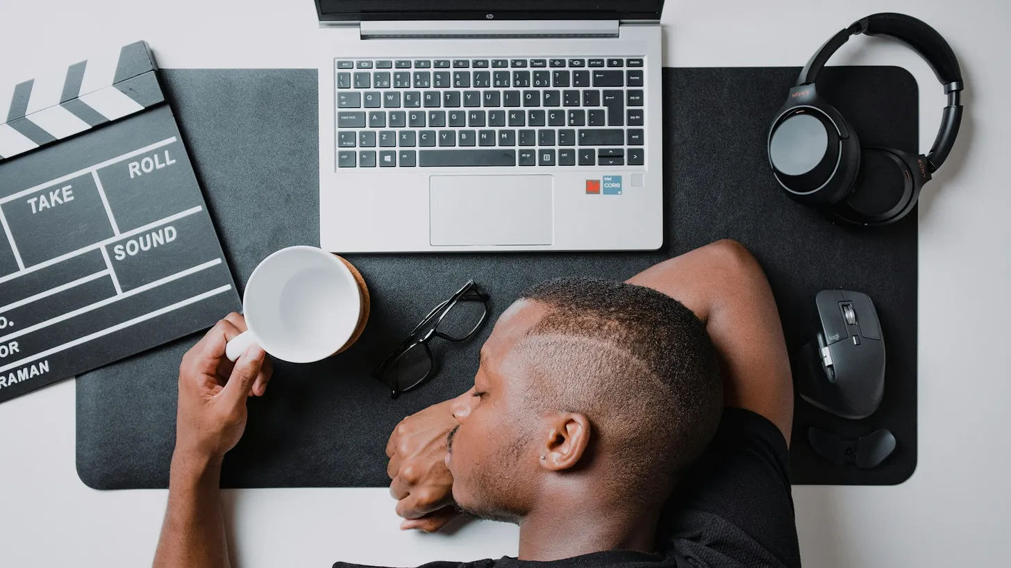 A man sitting at a desk with a laptop and headphones by Nubelson Fernandes from Unsplash