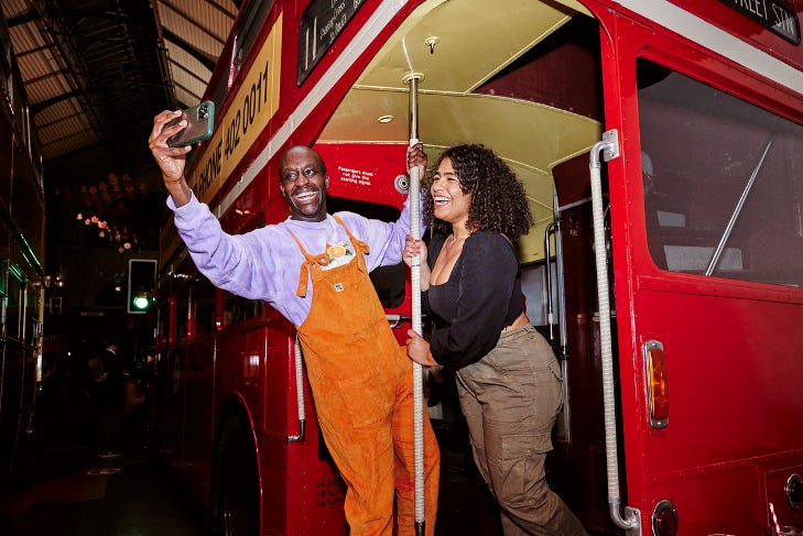 Two people posing for a selfie on the back of a vintage Routemaster