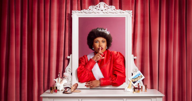 A woman wearing a tiara looking at herself in a dressing room mirror