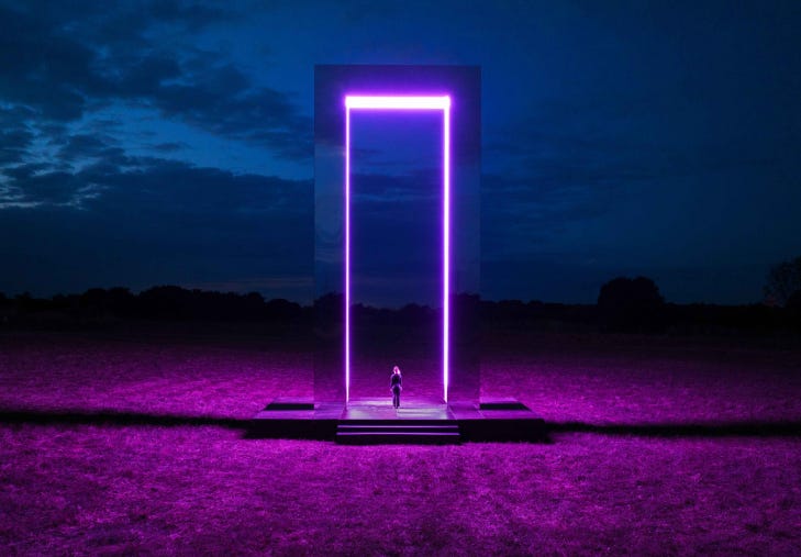 A person standing in front of a large illuminated door like a portal