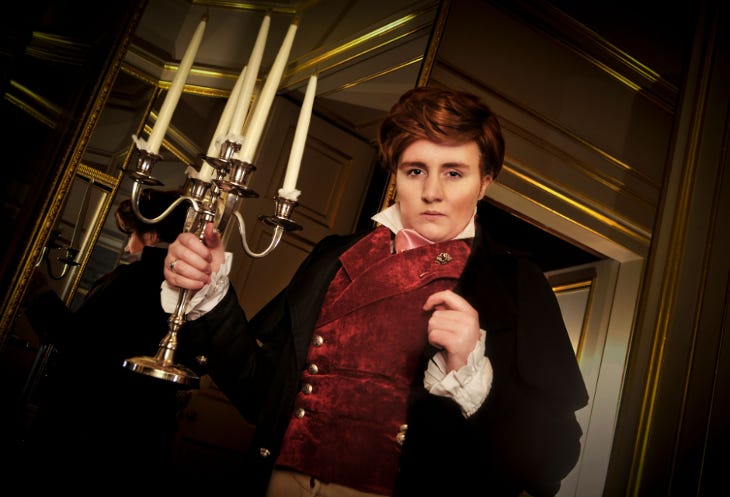 An actor in period costume holding a candleabra