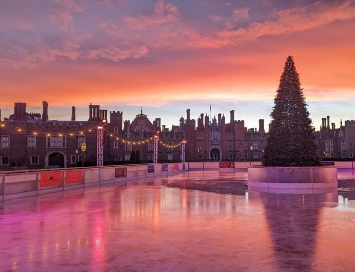 A pink/orange sky over Hampton Court Palace and its ice rink at sunset